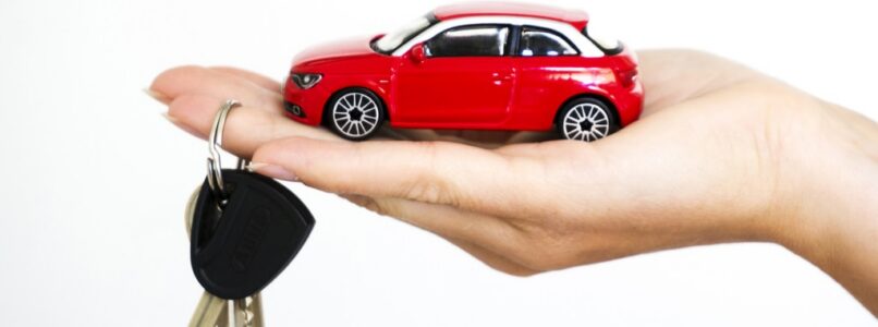 large hand holding small toy car with regular set of keys hanging on one finger