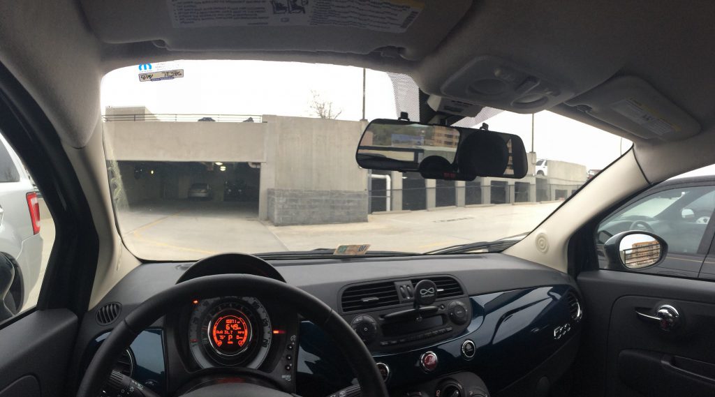 dash cam on rearview mirror, seen from car interior, looking through front windshield