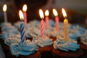 Cupcakes with lighted birthday candles, celebrating turning 65 -- time to enroll in Medicare!