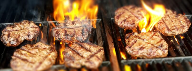 Sizzling burgers on a grill. Handle backyard fire responsibly