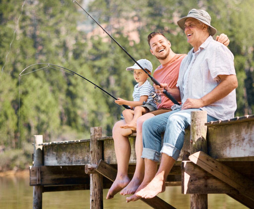 Happy father, grandfather and child fishing at lake together for fun bonding or peaceful time in nature. Dad, grandpa and kid enjoying life, catch or fish with rod by water pond or river in forest